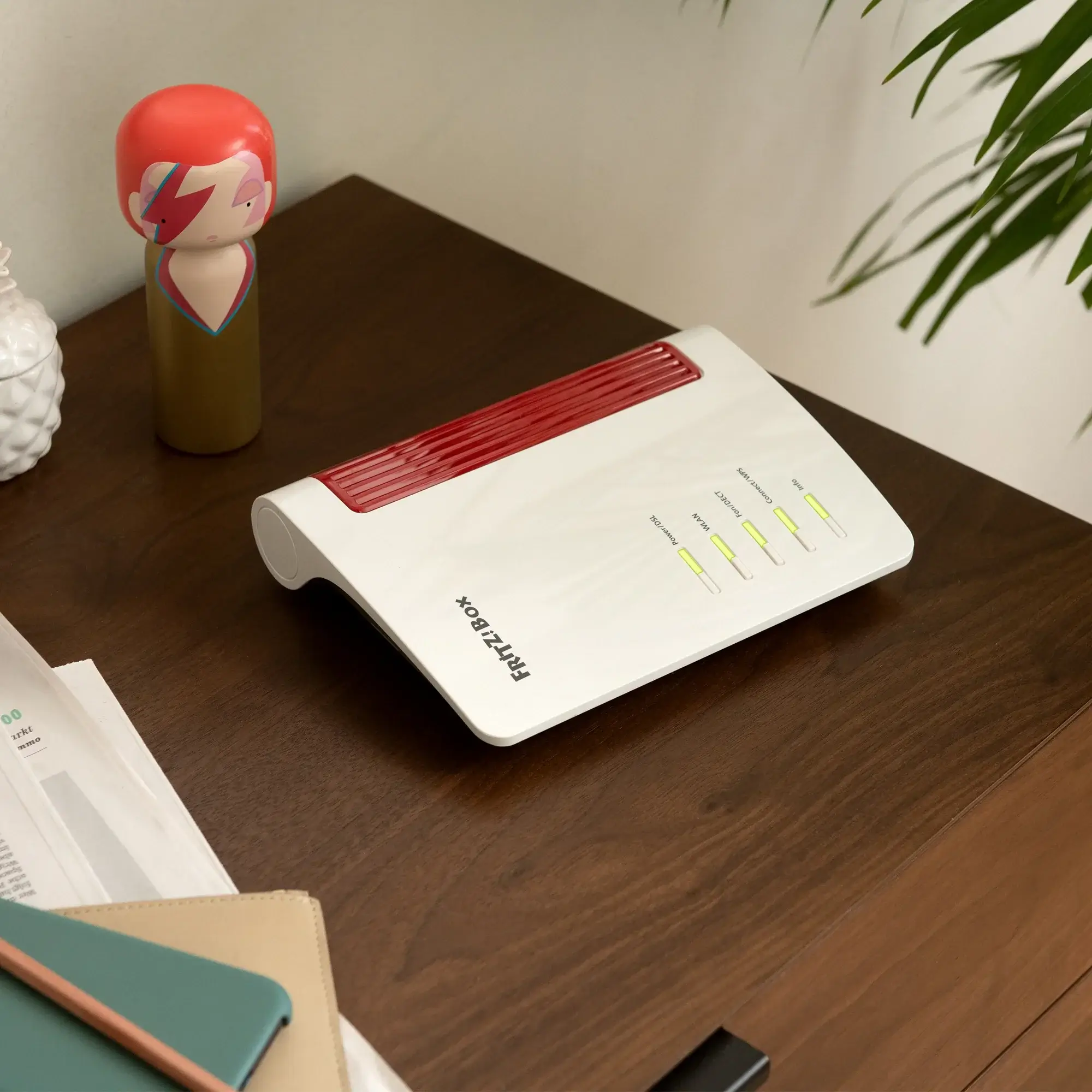 FRITZ!Box 7530 AX Router auf Holztisch, mit stylischer Figur im Hintergrund